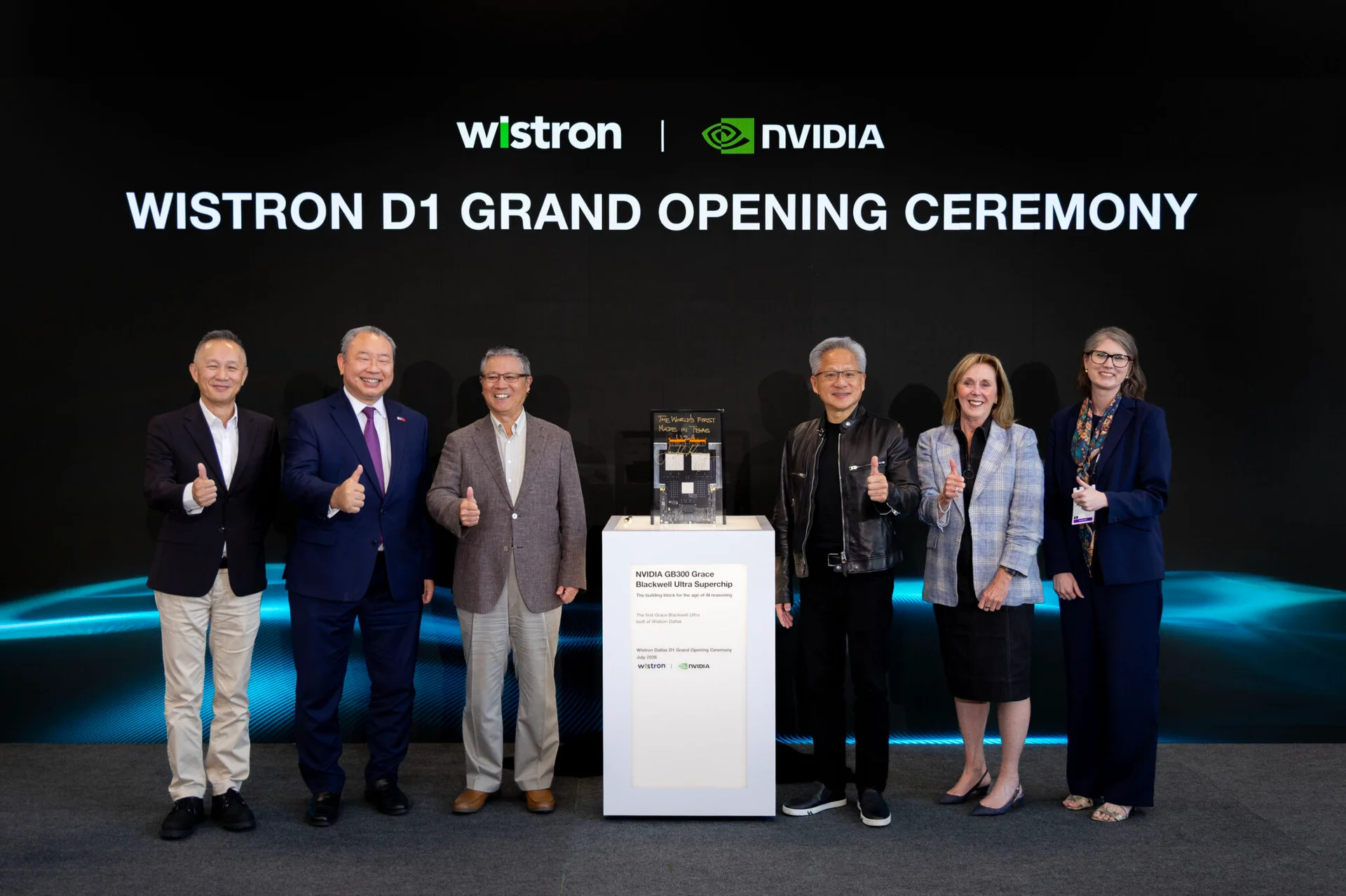 七位人士在Wistron D1盛大开幕典礼背景板前合影，背景板显示Wistron与NVIDIA标志及活动名称；中央展台上陈列着NVIDIA GB300 Grace Blackwell Ultra Superchip样品及其说明牌。